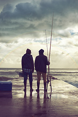 Image showing Back, pier and beach with fishermen, sunset or hobby with equipment or weekend break. People, ocean or friends with tools for activity or early morning with waves, shore or seaside with conversation