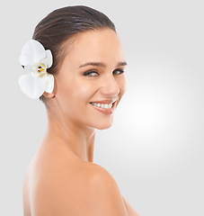 Image showing Girl, portrait and flower with glow for skincare in studio, beauty and natural makeup for blossom. Woman, orchid and hair with background, face and closeup with cosmetics dermatology for wellness