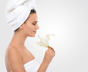 Image showing Woman, smile and flower in studio with skincare for glow, organic and natural beauty for lifestyle on mockup. Female person, thinking and towel for spa, hair care and hydration on white background