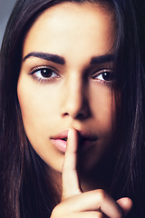 Image showing Woman, finger and quiet for mystery in studio portrait, secret and confidential information or emoji. Female person, private and shush icon on gray background, closeup and silence for announcement