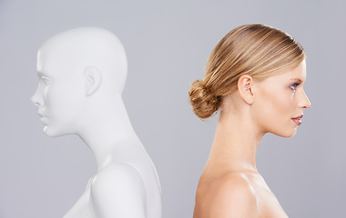 Image showing Studio, woman and profile of mannequin with beauty versus artificial standard, perfect and facial wellness. Girl, doll and clone of face for cosmetics, plastic surgery or makeup on grey background.