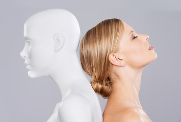Image showing Studio, girl and mannequin with perfect beauty versus artificial standard, identity and facial wellness. Woman, doll and face in profile for cosmetics, plastic surgery or makeup on grey background.