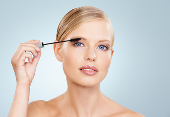 Image showing Beauty, mascara and portrait of woman in studio with confidence, makeup for lashes or facial glow. Glamour, cosmetics and face of girl on blue background with healthy skin shine, brush and wellness.