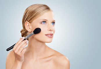 Image showing Beauty, brush and face of woman in studio with confidence, natural makeup or facial glow. Glamour, cosmetics application and girl on blue background with healthy skin shine, mockup and wellness.