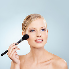 Image showing Cosmetics, brush and portrait of woman in studio with confidence, natural makeup or facial glow. Glamour, cosmetics and happy face of girl on blue background with healthy skin, shine and wellness.