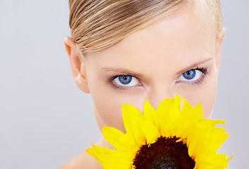 Image showing Portrait, skincare and woman with sunflower, wellness or dermatology on a white studio background. Face, person or model with shine or makeup with natural cosmetics or beauty with aesthetic or luxury