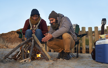 Image showing Men, sunset and campfire with warming hands, smile and happy from travel adventure and journey outdoor. Friends, ocean and sea with bonding, hug and vacation by the beach on holiday with fire