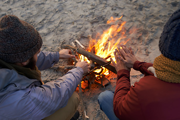 Image showing Hands, campfire and friends at beach on holiday, vacation and travel to warm up in winter outdoor. Flame, wood and people together by sand at seashore for leisure, adventure and top view in nature