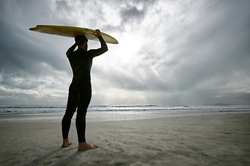 Image showing Man, surfer and wetsuit at beach for waves, sport or exercise on sandy shore in outdoor fitness. Rear view of male person or athlete with surfboard for surfing on ocean coast, sea or water in nature