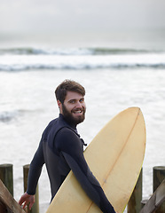 Image showing Happy man, portrait and surfer on beach for fitness, sport or waves on shore in outdoor exercise. Young male person with smile and surfboard for surfing challenge or hobby on ocean coast in nature