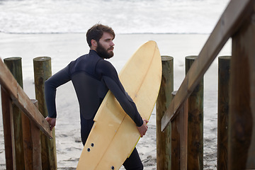 Image showing Man, surfer and beach by waves in fitness, exercise or extreme sports on outdoor shore. Rear view of male person or athlete with surfboard for surfing challenge or hobby at ocean coast, sea or nature