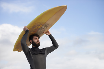 Image showing Man, surfboard and adventure at beach on holiday, weekend and sports for fitness in water. Male person, balance and cloudy sky on tropical island, wetsuit and travel on vacation or getaway for peace