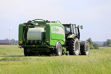 Image showing Tractor and Baler Baling Silage on Sunny Day