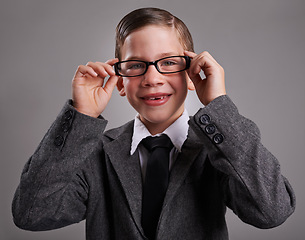 Image showing Portrait, costume and boy with glasses, business and Halloween dress up on a grey studio background, Face, person and model with vision and eyewear with child development and smile with retro clothes