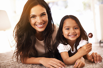 Image showing Happy, mom and portrait with child and lollipop on floor in relax for family bonding, love or care together at home. Face of mother, parent and little girl, daughter or kid with smile in living room