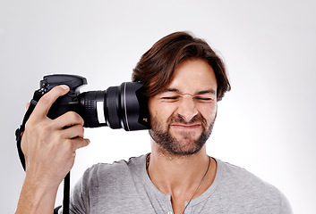 Image showing Photographer, digital and man pressing his camera against his ear on a white studio background. Artistic, person or model with equipment and technology with creativity or media with deadline and tool