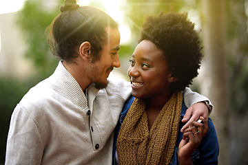 Image showing Park, hug and happy interracial couple together with trees, sunshine and morning embrace with love. Romance, smile and outdoor date in nature, man and woman with diversity, connection and care.