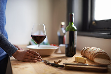 Image showing Hand, red wine in glass and bread on table, dinner meal prep and drink to relax while cooking. Person at home, food and beverage to enjoy for nutrition, health and wellness with alcohol and supper