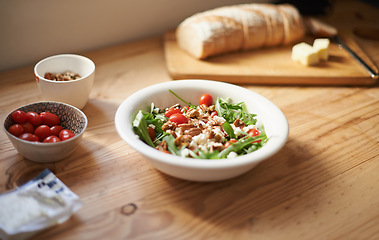 Image showing Healthy, salad and lunch on table in kitchen closeup with bread for nutrition and diet in home. Tomato, lettuce and cooking with nuts in food with bowl on counter for dinner and meal prep in house