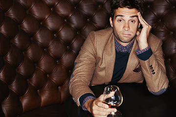 Image showing Portrait, bored and man drinking in a club, expression and relax with event and afterparty. Face, guy on a sofa or person with alcohol and annoyed with a glass, headache and frustrated with culture