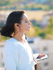 Image showing Woman, city and earphones with tablet, podcast or music for listening or relaxing while thinking. Worker, technology and mental health with audio, mindfulness and media for wellness and ideas or zen