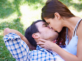 Image showing Couple, kiss and picnic on grass for love, bonding and connection on holiday in park outdoors. Relax, man and woman with romance for healthy relationship, commitment and date on vacation in Miami