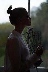 Image showing Female person, flowers and window for in home, dark room and alone aesthetic for contemplation or artistic. Women, dim light and morning with thinking, creative and mysterious style for loneliness