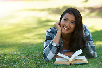 Image showing Woman, thinking and reading book on grass, literature and smiling for fiction or fantasy story. Female person, nature and relaxing on lawn for knowledge, daydreaming and student studying in garden