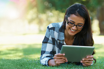Image showing College, woman and reading on tablet in park with research, project or learning outdoor on campus. University, student and girl streaming online with ebook, education and studying on grass in garden