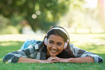 Image showing Woman, headphones and streaming music on grass, radio and internet for podcast in outdoors. Female person, happy and relaxing on lawn, weekend playlist and subscription for audio or sound on vacation