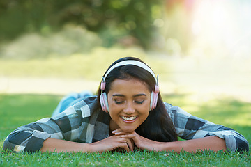 Image showing Woman, headphones and streaming song on grass, peace and calming podcast in outdoors. Female person, happy and relaxing on lawn, weekend playlist and subscription for audio or sound on vacation