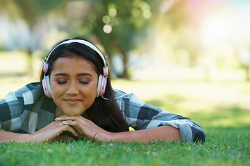 Image showing Music headphones, park or woman on grass to relax for rest in garden, nature or field with smile or peace. Eyes closed, streaming or calm person on break with playlist for radio, podcast or wellness