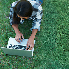 Image showing Above, grass and person typing on laptop in park with college research, project or learning on campus. University, student and girl reading online with ebook, education and study on lawn in garden