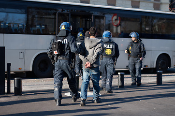 Image showing Police officer, arrest and person in street for crime, safety and bus for crowd control in city. People, law enforcement and vehicle for danger, warning and transportation on urban road in Copenhagen