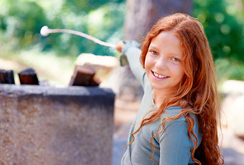 Image showing Girl, smile and portrait by fire with marshmallow for camping adventure, summer and vacation for fun outdoors. Child, happy and face by barbecue with stick on holiday, outside and freedom to relax