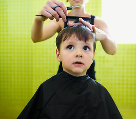 Image showing Child, boy and barber with haircut at salon for grooming, hairstyle or serious with scissors. Hairdresser, person or kid for hair treatment, haircare and hairdressing with comb, confidence or looking