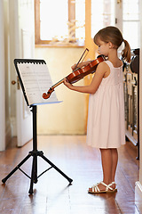 Image showing Violin, girl and kid playing in home, learning and practice for education, music or reading sheet. Art, fiddle or child with bow for talent, creative or hobby in house with acoustic string instrument