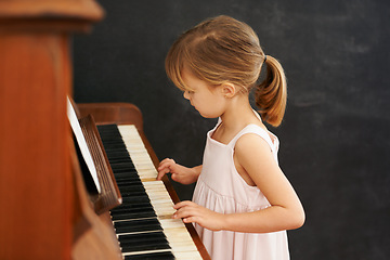 Image showing Piano, playing and kid in home for learning, practice and classical education with musical notes. Training, melody and girl with talent, creative or hobby with instrument, child development or skill