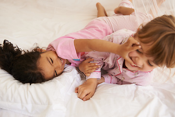 Image showing Children, playing and fight on bed on weekend, fun and tickling with laughing on sleepover in home. Young girls, love and bonding in bedroom in pyjamas, friends and wrestle game on holiday in house