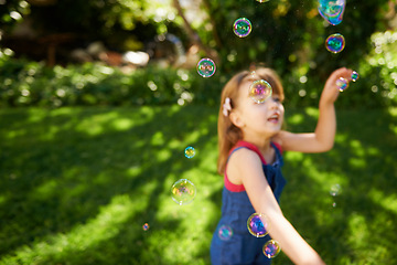 Image showing Child, bubbles and garden grass for playing in summer sunshine in backyard for holiday, carefree or happy. Kid, girl and youth in California in outdoor nature or fun for vacation, weekend or game