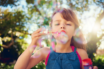 Image showing Child, blowing and bubbles in garden or playing in summer sunshine in backyard for holiday, carefree or happy. Kid, girl and youth in California in outdoor nature or fun for vacation, weekend or park