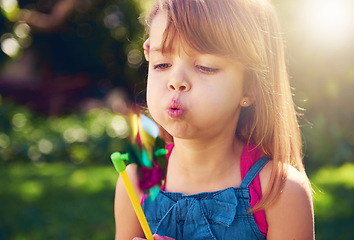 Image showing Young girl, backyard and blowing pinwheel, garden and enjoying freedom of outside and fun. Pretty little child, outdoor and summer for playing, toy and windmill for holidays and nature sunshine