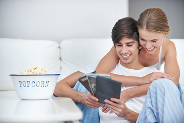 Image showing Couple, popcorn and choice for movie, living room and date for comfortable home bonding. People, relationship and love with film, relaxation and smile for happiness or break with snack for eating