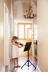 Image showing Violin, girl and child playing in home, learning and practice for education, music or performance. Art, fiddle and kid with bow for talent, creative or hobby in house with acoustic string instrument