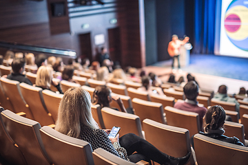 Image showing Speaker giving a talk in conference hall at business event. Rear view of unrecognizable people in audience at the conference hall. Business and entrepreneurship concept.