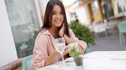 Image showing Happy Woman Enjoying a Drink at an Outdoor Cafe