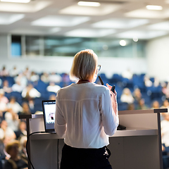 Image showing Female speaker giving a talk on corporate business conference. Unrecognizable people in audience at conference hall. Business and Entrepreneurship event.