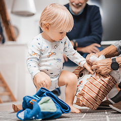 Image showing Cute little blond Caucasian toddler unpacking Christmas or Birthday present. Adorable small infant baby boy opening gift