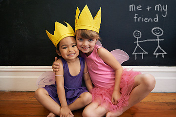 Image showing Little girls, friends and portrait with embrace, crown and smile for love and happiness. Children, youth and hug for face, fun and bonding with blackboard and fairy princess costume for dress up