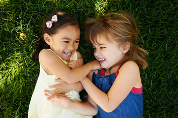 Image showing Tickling, nature and girl children on grass play together in outdoor park or garden on vacation. Smile, bonding and high angle of young kid friends having fun on lawn in field on holiday or weekend.